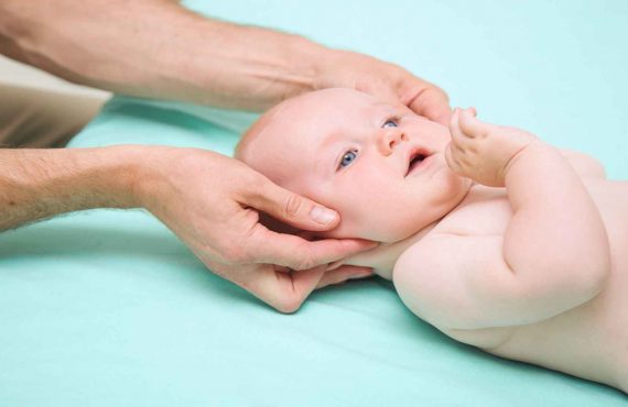 Baby Boy Getting Head Examined By Chiropractor - Family Chiropractor - Henry Chiropractic - 1602 N 9th Ave, Pensacola, FL 32503 - (850) 435 7777 - https___drcraighenry.com
